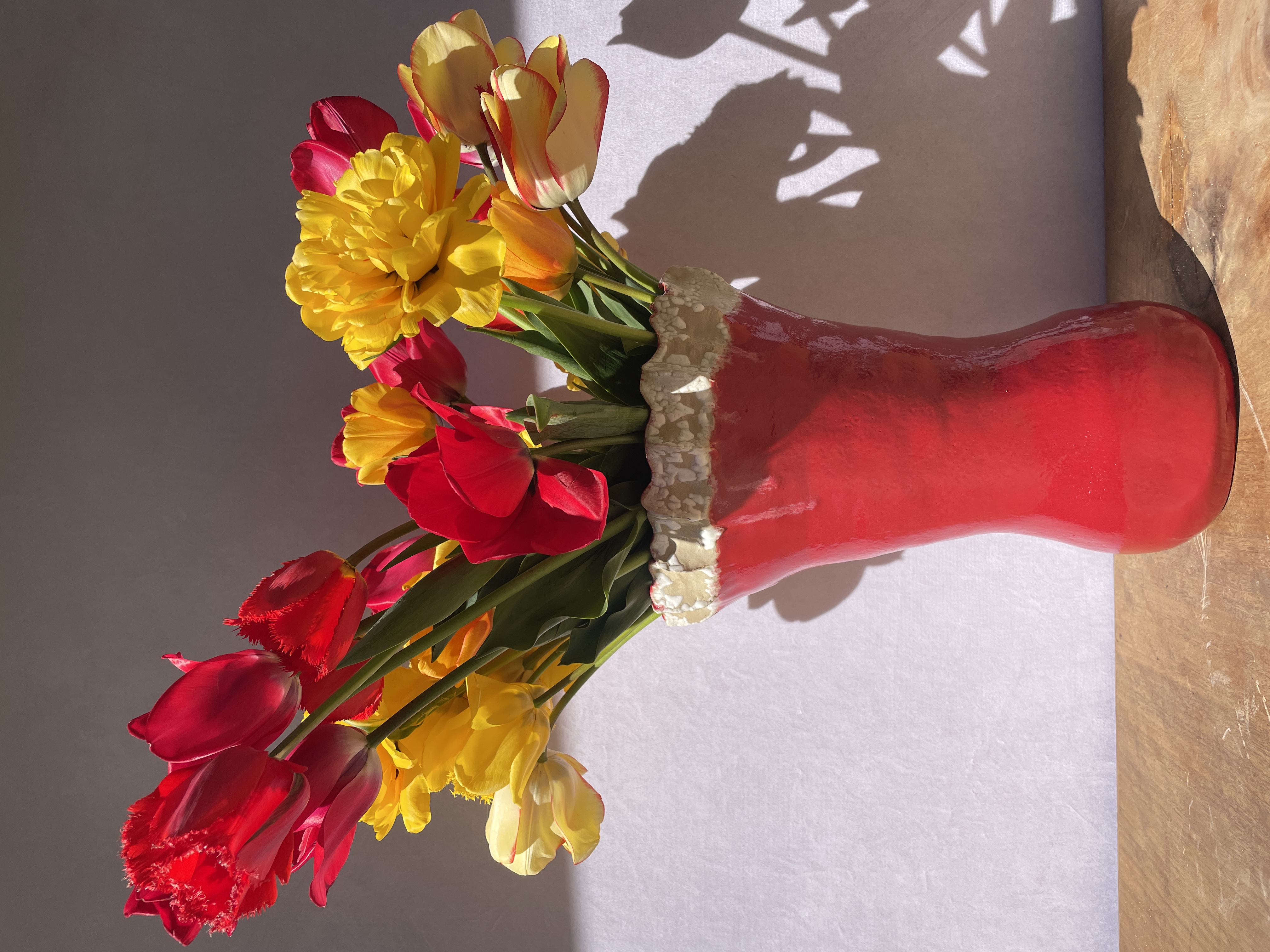 Roter Keramiktopf mit gelben und roten Tulpen